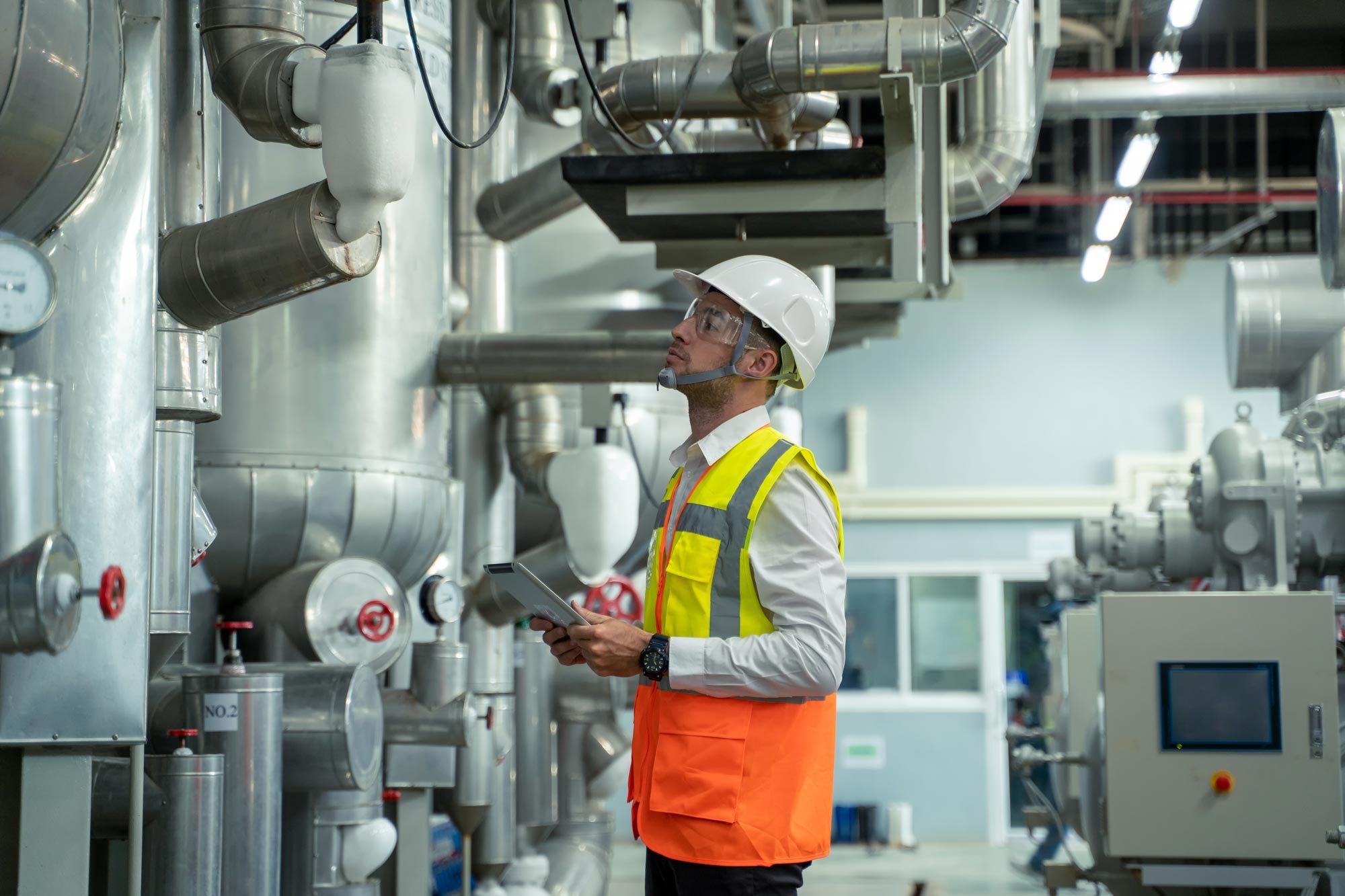 Engineer checking and maintenance technical data of system equipment condenser Water pump and piping air compressor system at manufacturing factory.